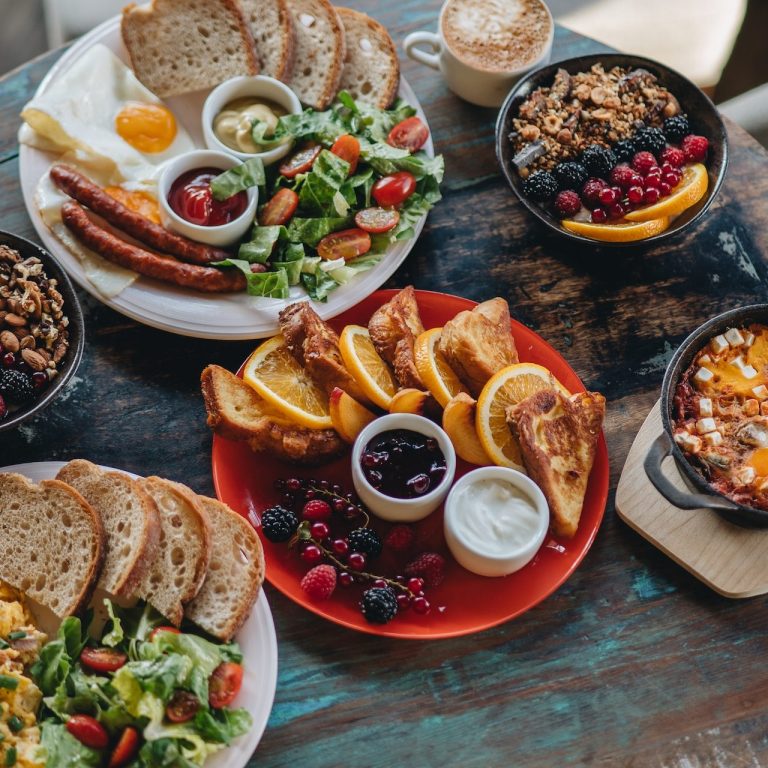 Auf dem Bild ist eine Auswahl von Spezialitäten für das Frühstück zu sehen, unter anderem Brot, Salat, eine Bowl und Pancakes.